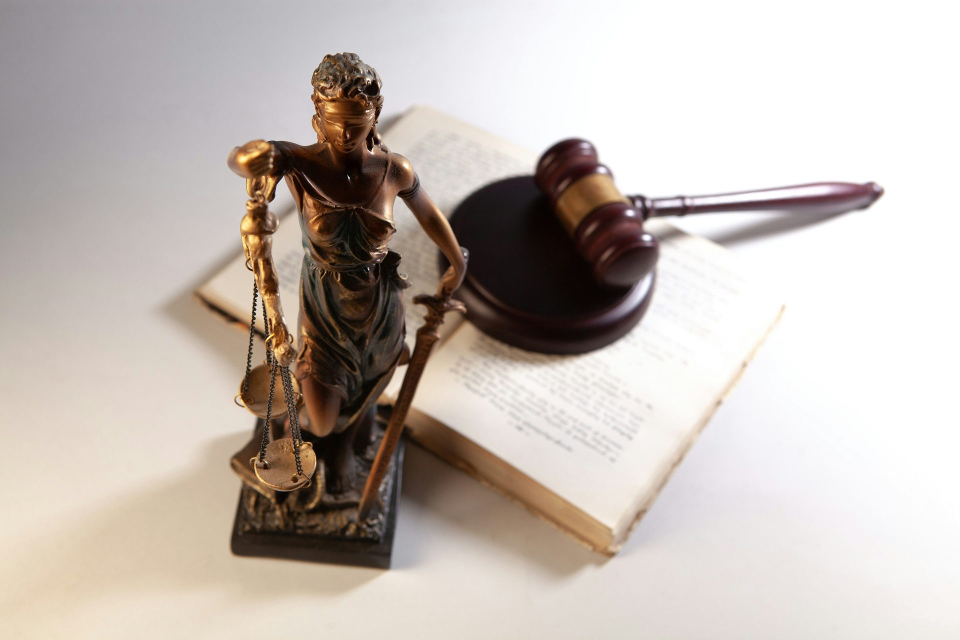 Statue de la Justice, marteau de juge et livre ouvert sur une table.